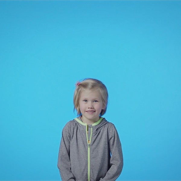 A young girl talking to camera in a blue studio.